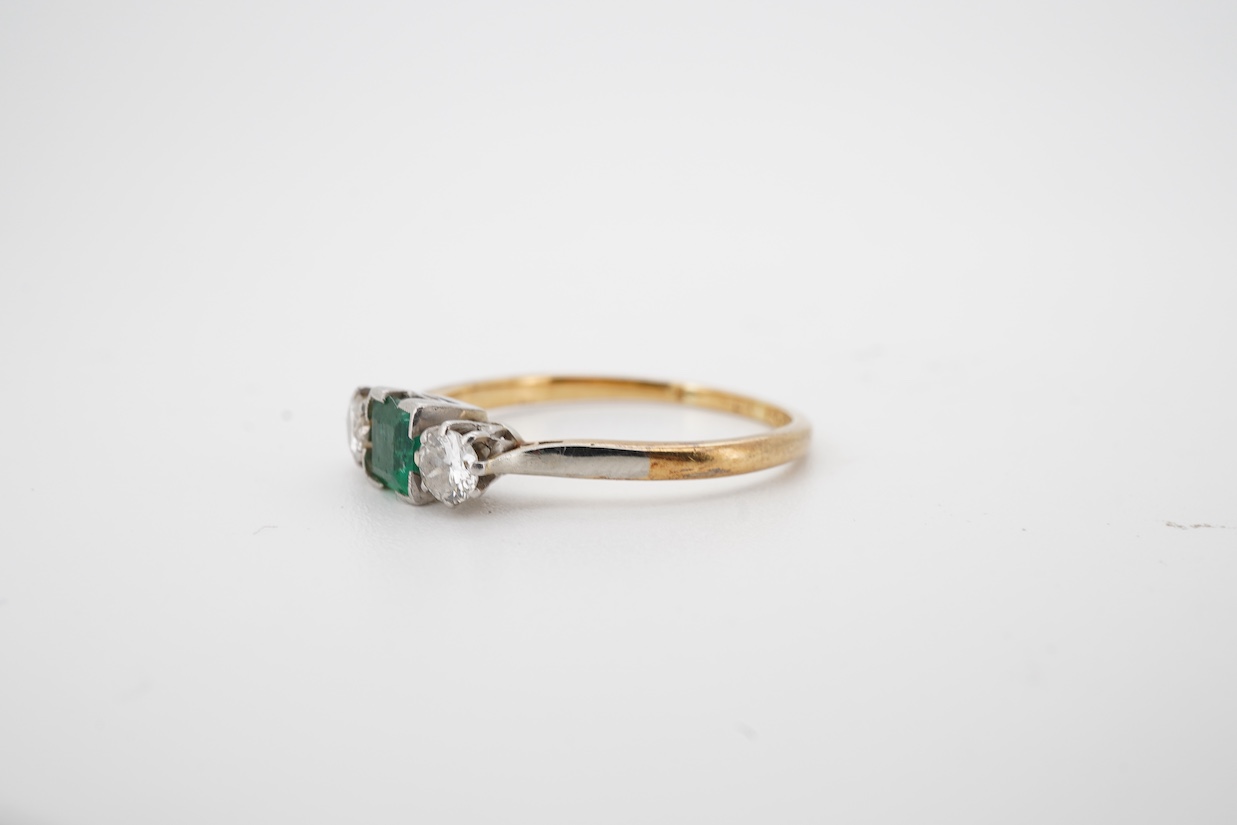 A yellow metal, single stone emerald and two stone diamond set ring, the emerald measuring approximately 4.3mm, the diamonds approximately 0.15ct each, the shank stamped with maker's mark HS and 'Plat', size P/Q.